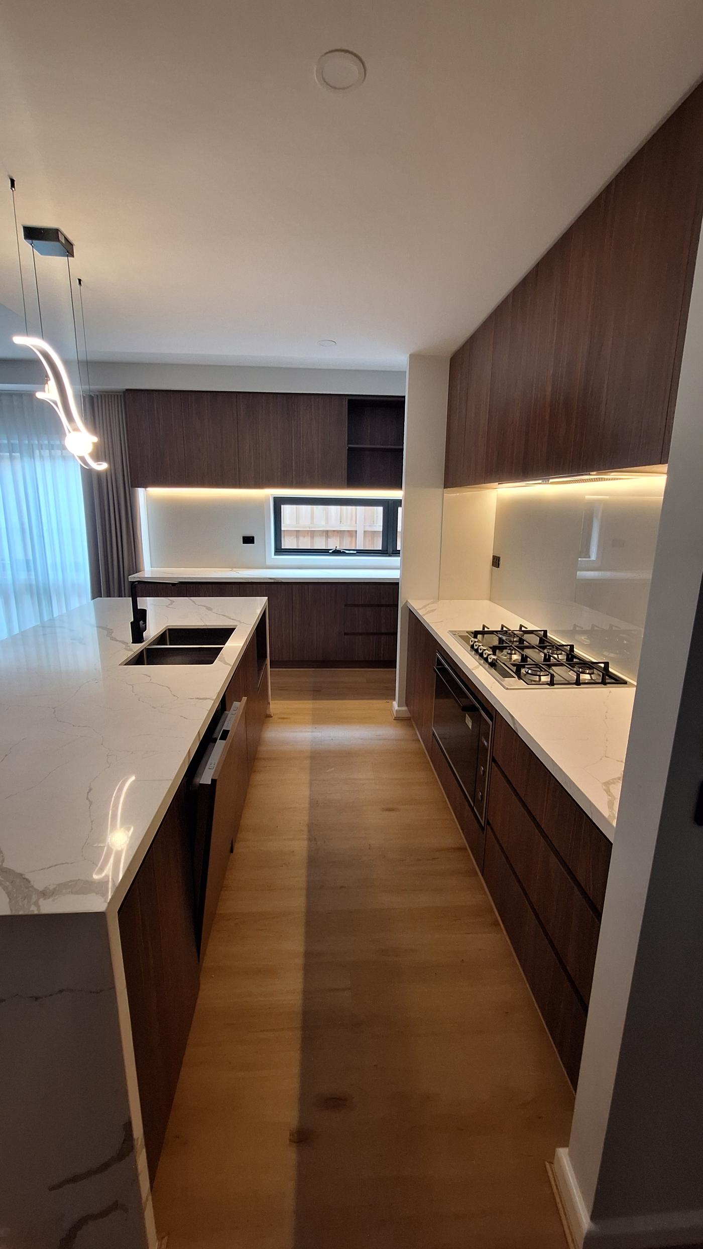 Kitchen — dark timber cabinetry, stone benchtops, gas cooktop